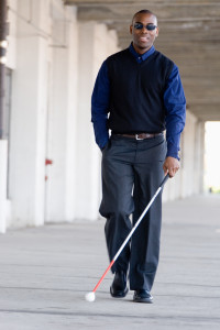 Visually impaired Black man walking with white cane