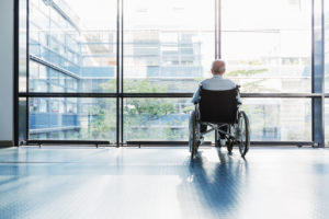 Person in wheelchair looks out bright, sunny window