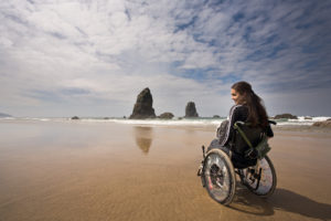 Woman in a wheelchair nears the water on a beach